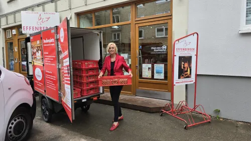 Woman on an e-cargobike from Bäckerei Effenberger in front of a branch, ready for sustainable delivery.
